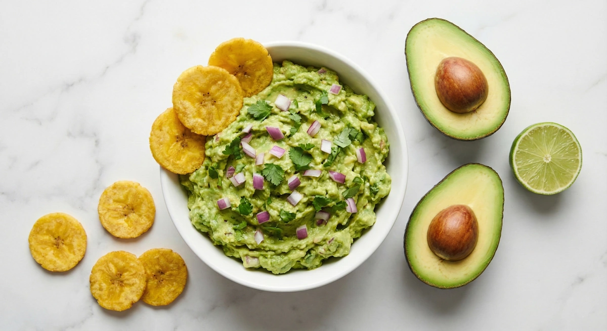 Cremige Guacamole in einer weissen Schale serviert mit knusprigen salzigen Kochbananenchips – eines unserer besten Kochbananenchips Rezepte für einen glutenfreien Apéro.