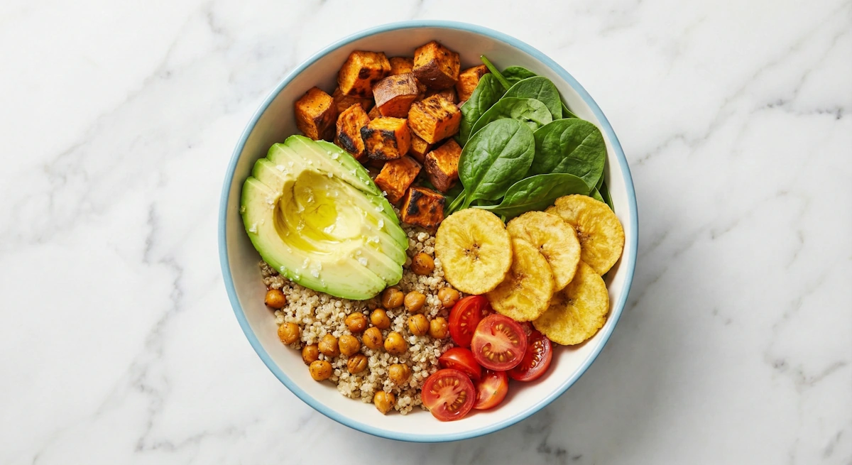 Bunte Quinoa Bowl mit Avocado, Kirschtomaten, Kichererbsen, Suesskartoffeln und salzigen Bananenchips als gesundes Topping.